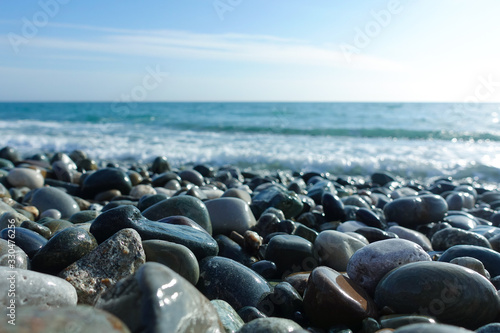 Sea shore with pebbles. wet sea pebbles on the beach and quiet sea surf