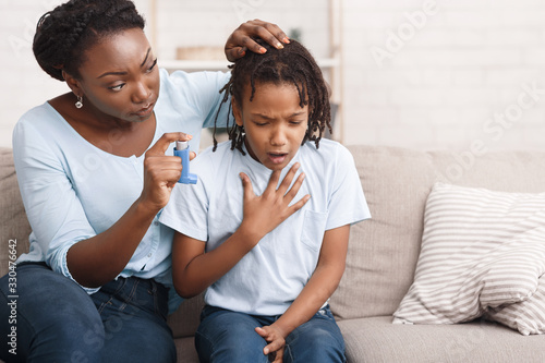 Afro mother holding asthma inhaler for daughter photo