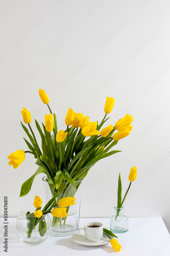 bouquet of yellow tulips is on the table opposite white wall. bouquet of yellow tulips is on the table opposite white wall.