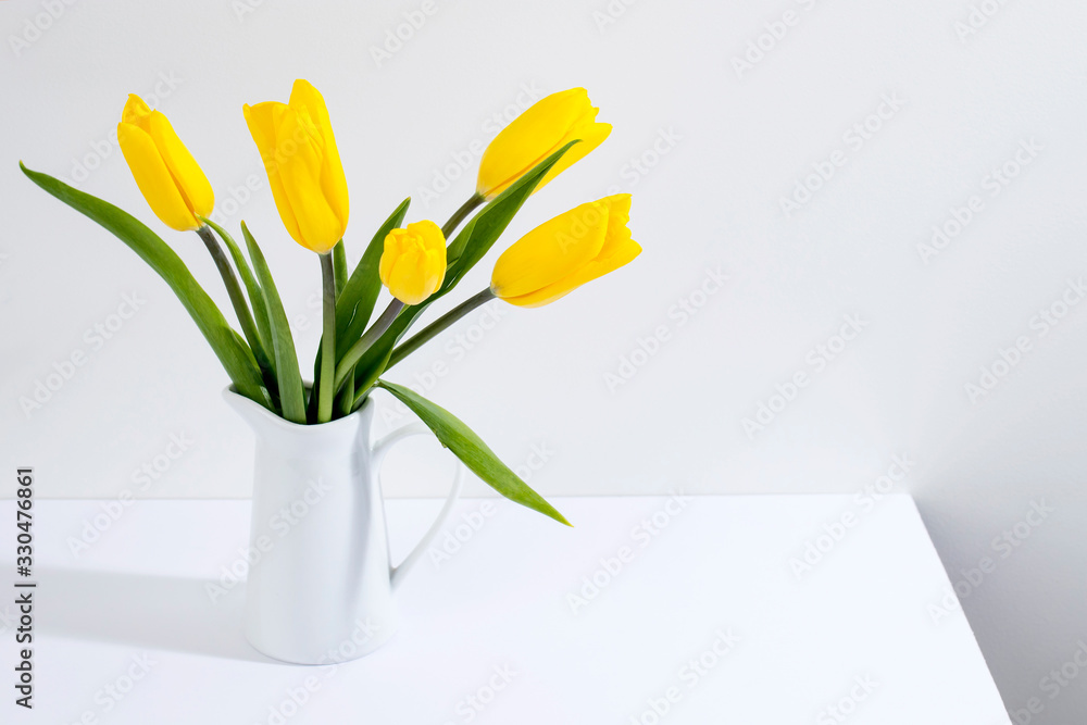 bouquet of yellow tulips is on the table opposite white wall. bouquet of yellow tulips is on the table opposite white wall.