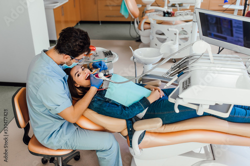 The woman came to visit the dentist. She sits in the dental chair. The dentist bent over her.