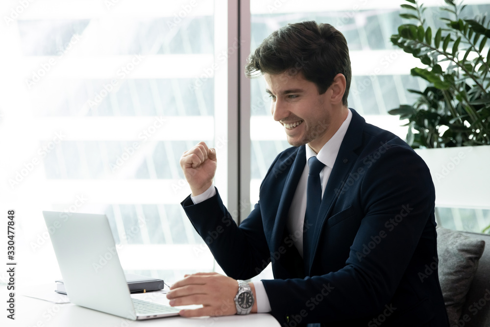 Overjoyed millennial male employee feel euphoric win online business lottery or grant on computer, happy young businessman triumph get good financial results statistics, reward, victory concept Overjoyed millennial male employee feel euphoric win online business lottery or grant on computer, happy young businessman triumph get good financial results statistics, reward, victory concept