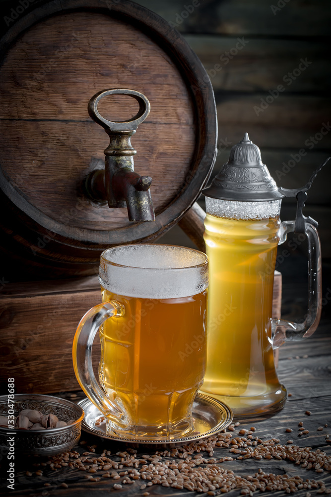 Light frothing beer in a glass, on an old background. Light frothing beer in a glass, on an old background.