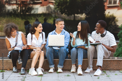 Multi-Ethnic Students Sitting Outdoors With Laptop  Preparring For Classes Together