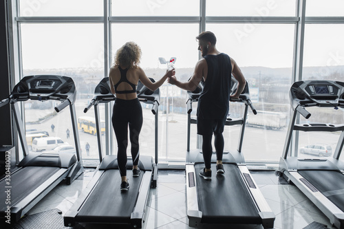 Photo of the back, young sports couple making cardio workout in modern gym