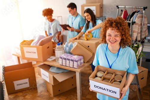 Woman and her colleague working in homeless shelter. Cheerful food drive manager. Happy diverse group of volunteers at food bank. Happy woman volunteers at a food bank photo