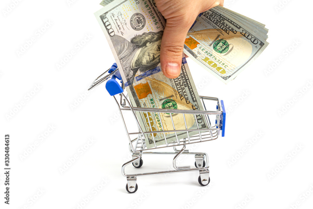 shopping basket with blue inserts a hand puts a hundred-dollar bill from a bundle into it on a white background. isolate shopping basket with blue inserts a hand puts a hundred-dollar bill from a bundle into it on a white background. isolate