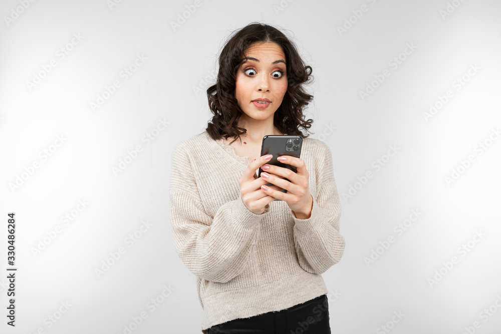 nice girl in a white blouse with a smartphone in hand on a white background with copy space nice girl in a white blouse with a smartphone in hand on a white background with copy space