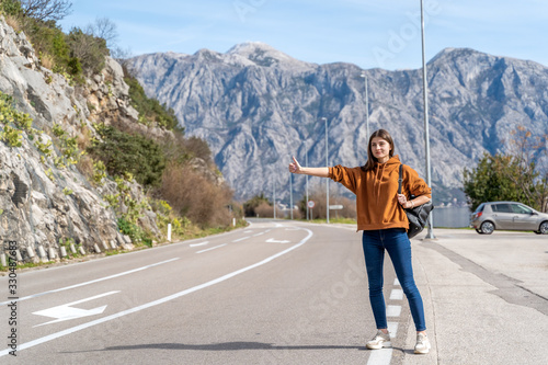Travel woman hitchhiking. Beautiful young female hitchhiker by the road during vacation trip in mountains Montenegro © Elena Sistaliuk