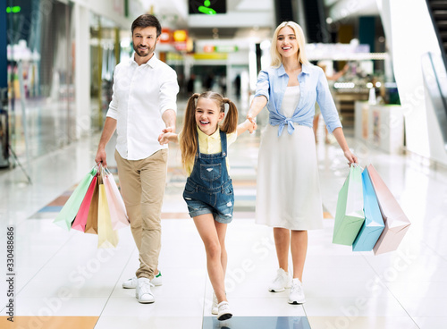 Family Of Three Carrying Shopper Bags After Shopping In Mall