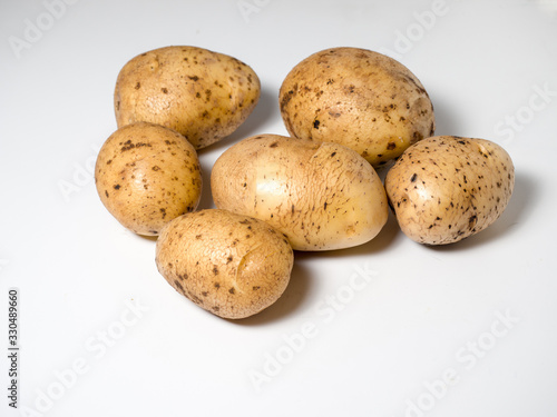 Several potatoes on a white surface. Studio photography