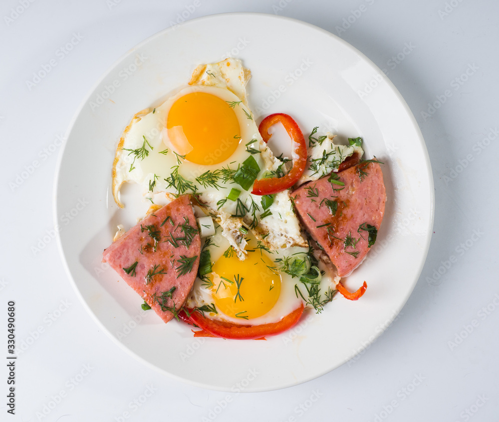 Fried sausage fried eggs on a white round plate. Top view Fried sausage fried eggs on a white round plate. Top view