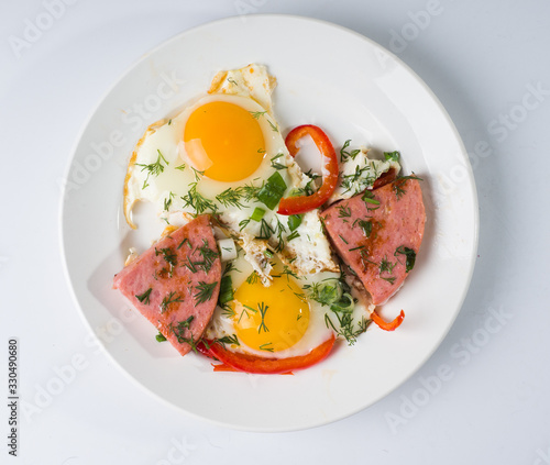 Fried sausage fried eggs on a white round plate. Top view