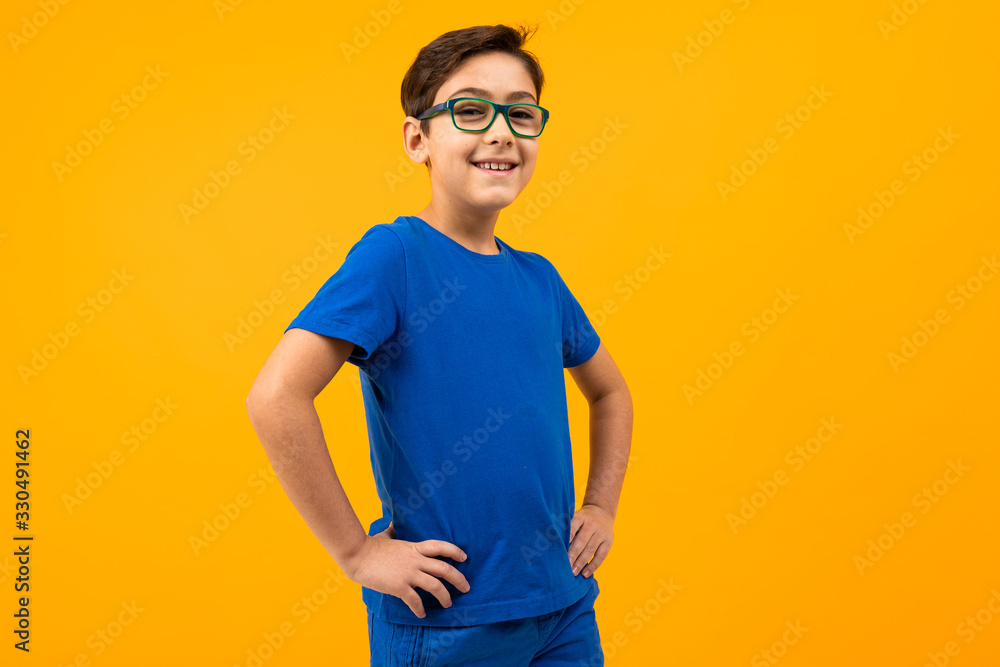boy in a blue T-shirt with glasses posing on a yellow background with copy space boy in a blue T-shirt with glasses posing on a yellow background with copy space