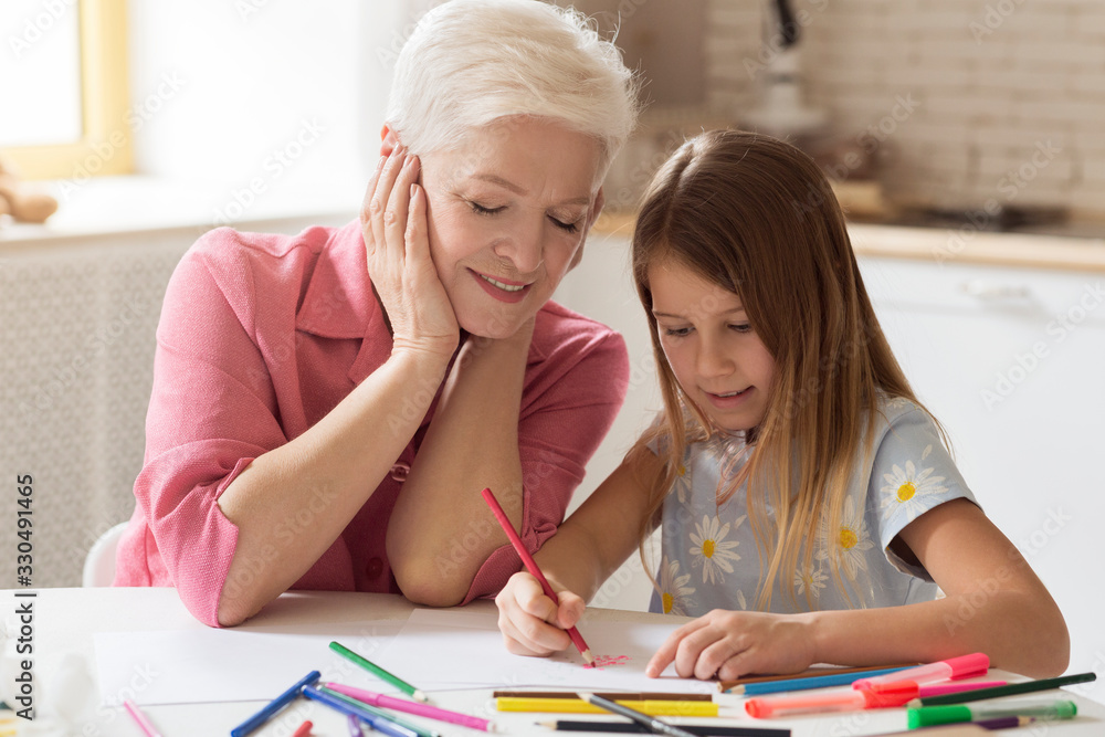 Grandparent and grandchild drawing with color pencils in kitchen Grandparent and grandchild drawing with color pencils in kitchen
