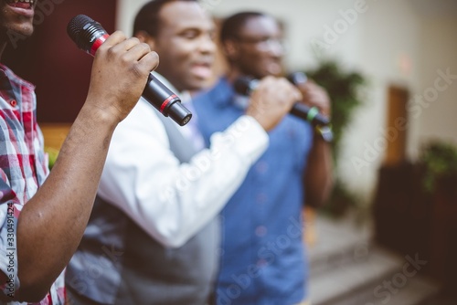 Valokuva Group of African-American friends singing with microphones at the church