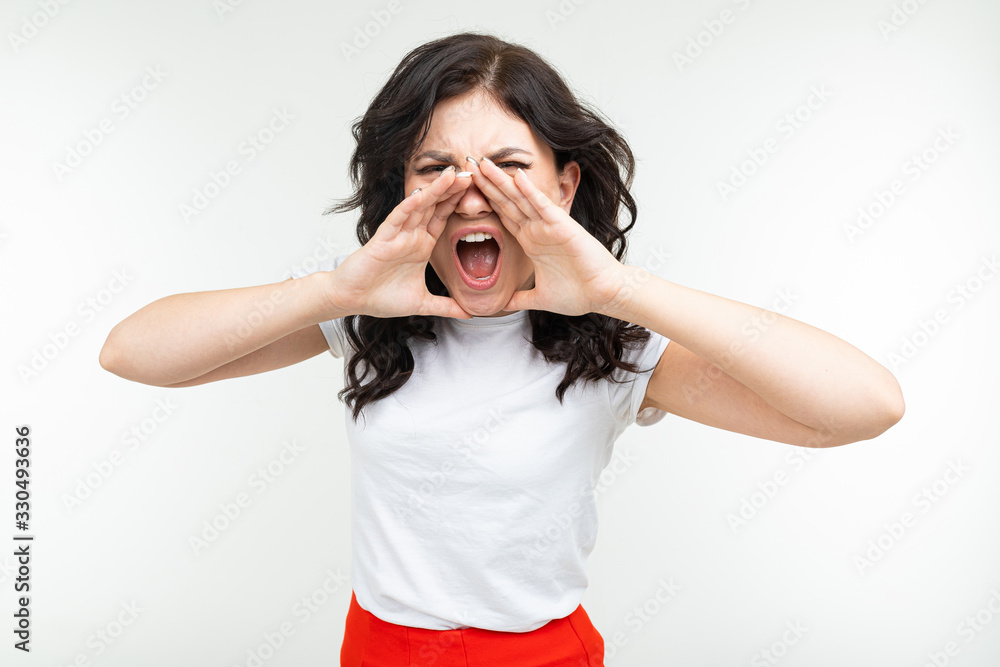 brunette girl in a white t-shirt screaming about discounts on a white studio background brunette girl in a white t-shirt screaming about discounts on a white studio background