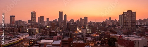 A beautiful and dramatic panoramic photograph of the Johannesburg city skyline, taken on a golden evening after sunset. photo