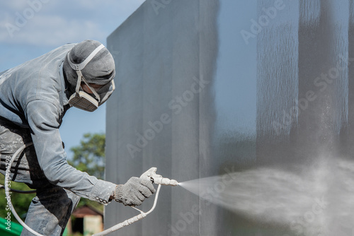 Airless Spray Painting, Worker painting on steel wall surface by airless spray gun for protection rust and corrosion.