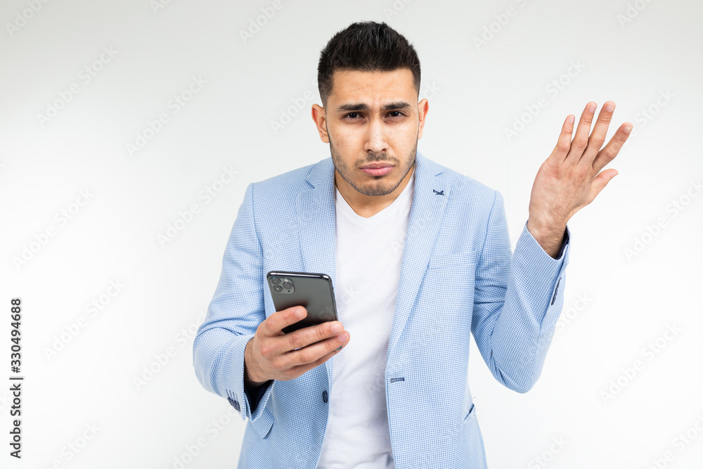 stylish brunette man in a blue classic jacket is suspiciously studying information on the phone on a white background stylish brunette man in a blue classic jacket is suspiciously studying information on the phone on a white background