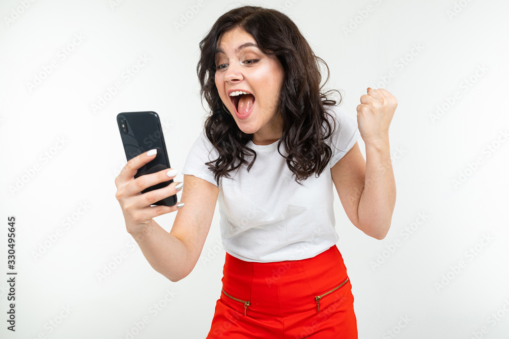 happy girl dancing with joy realizing about winning in a draw on the Internet holding a phone in her hand on a white background happy girl dancing with joy realizing about winning in a draw on the Internet holding a phone in her hand on a white background