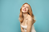 Portrait of beautiful young woman laughing on blue background