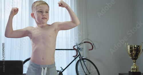Happy child doing sports at home, boy fitness training dumbbells