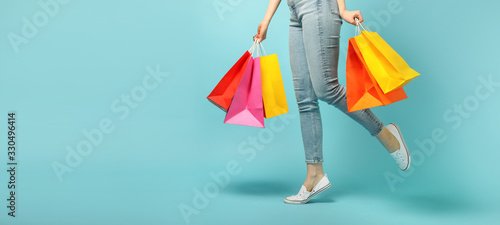 Beautiful young woman and shopping bags on blue background photo