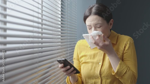 Woman chatting with her phone and sneezing photo