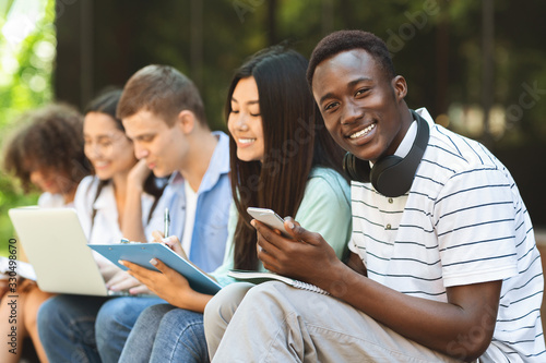 Happy African American Teen Guy Studying With His College Friends Outdoor