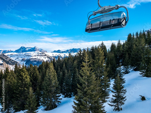 View of coniferous forest and mountains from a chair lift. View of a ski resort piste and Dolomites mountains in Italy from Passo Pordoi pass. Arabba, Italy photo