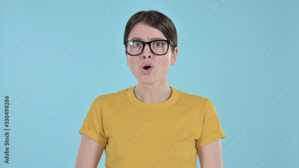 The Young Woman Feeling Shocked and Annoyed on Blue Background