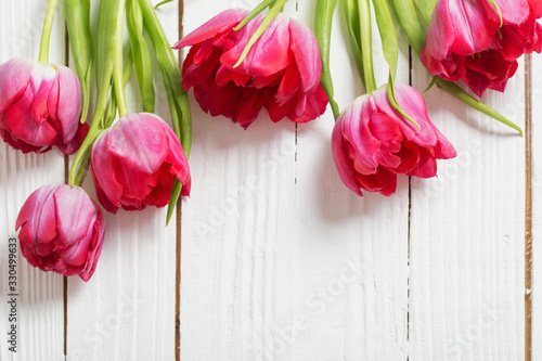 red tulips on white wooden background © Siarhei