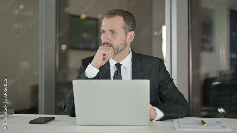 The Pensive Businessman Thinking and working on Laptop at Night The Pensive Businessman Thinking and working on Laptop at Night