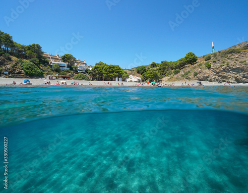 Spain Mediterranean sea, beach coastline in summer vacations with sand underwater, split view over and under water surface, Costa Brava, Colera, Catalonia