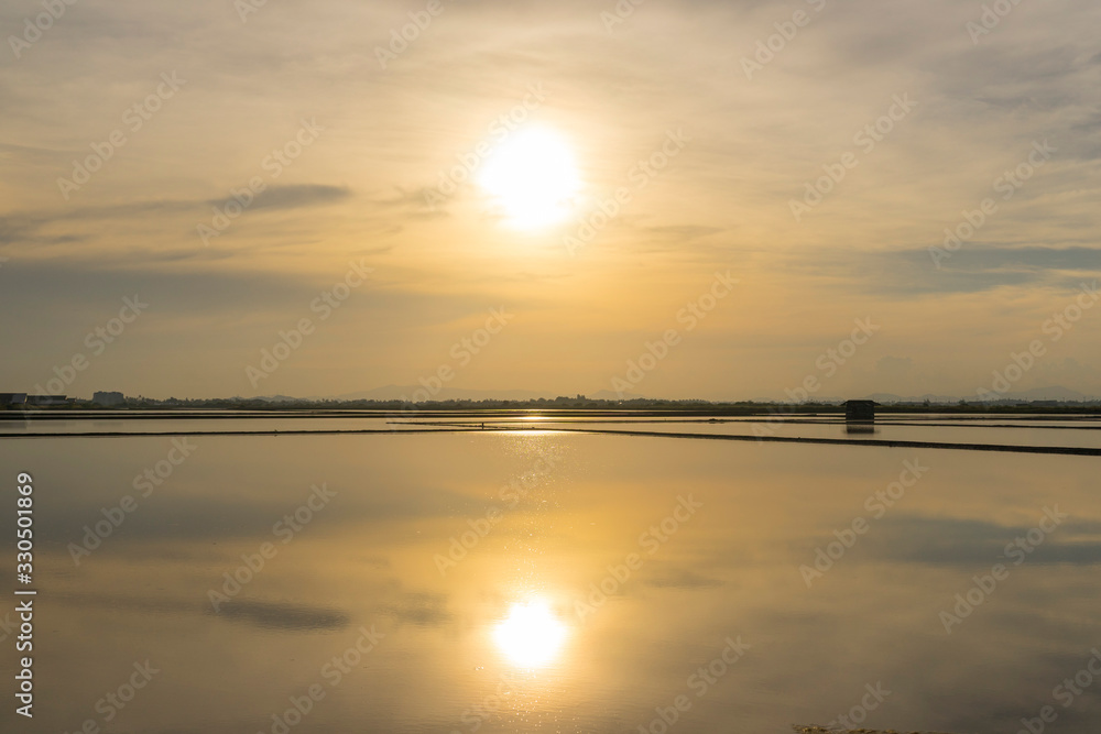 Salt farm in the morning with sunrise sky and clouds. Landscape of sea salt field in Thailand.