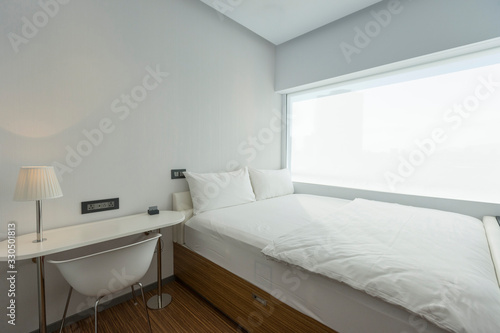 Tiny bedroom with white sheets and white pillows in the bed