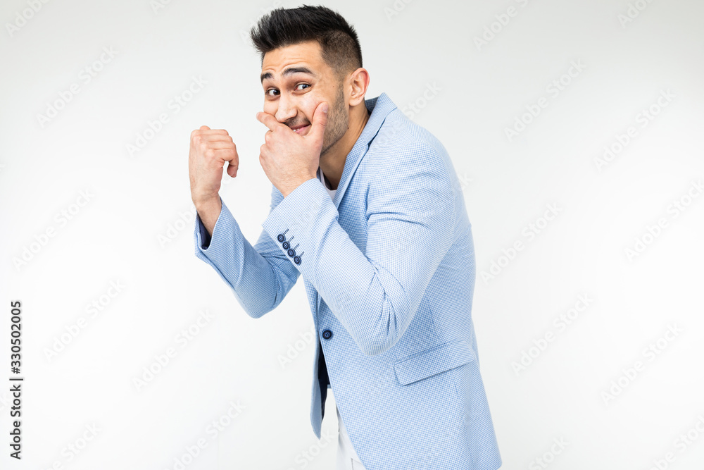 serious man in a jacket laughs covering his mouth with his hand on a white studio background serious man in a jacket laughs covering his mouth with his hand on a white studio background