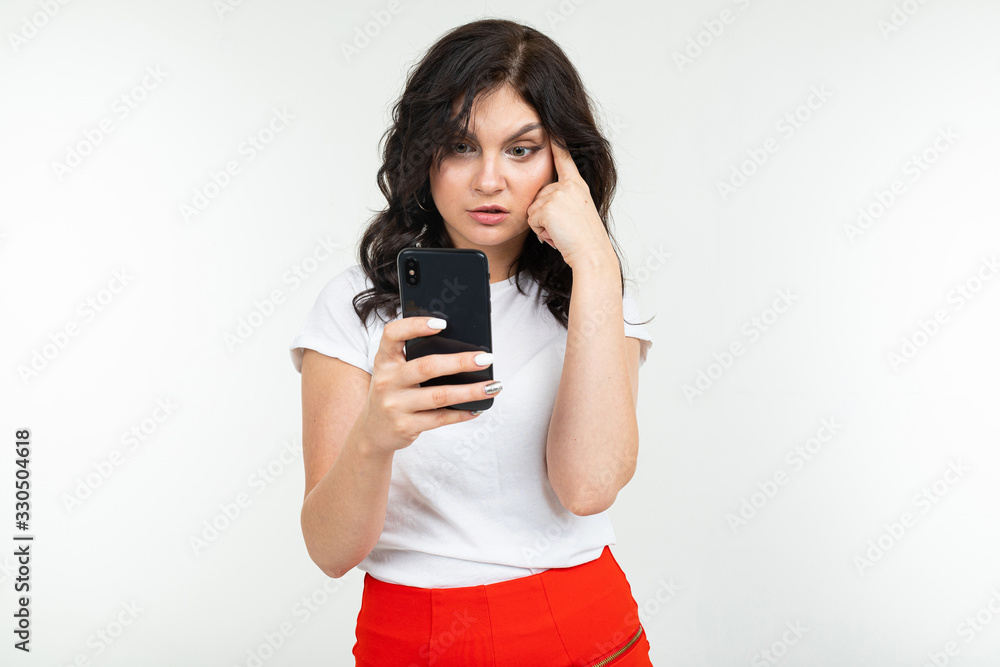 brunette girl is surfing the internet holding a phone in her hands on a white isolated background brunette girl is surfing the internet holding a phone in her hands on a white isolated background