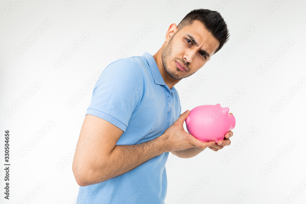 man looks suspiciously holding a piggy bank in his hands on a white studio background man looks suspiciously holding a piggy bank in his hands on a white studio background