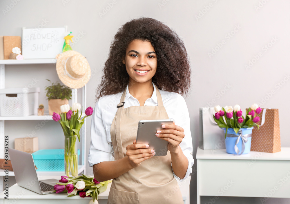 Woman florist at her workplace, near table with laptop and flowers Woman florist at her workplace, near table with laptop and flowers