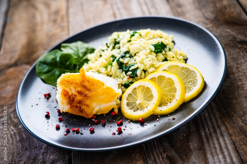 Risotto with fried cod on wooden background Risotto with fried cod on wooden background