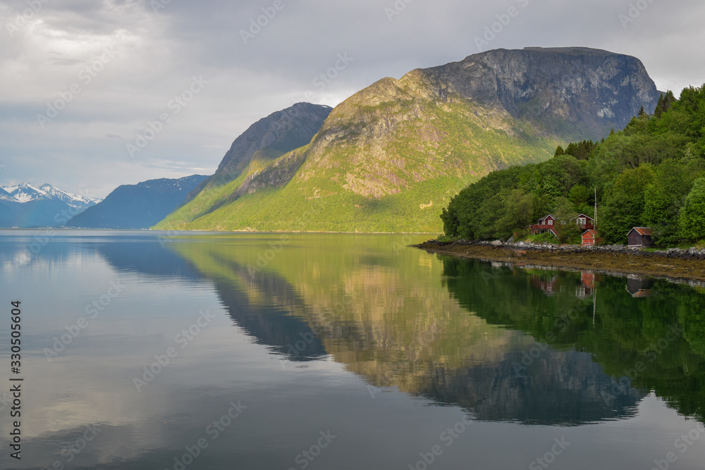Mandalen, Norway  . Beautiful coastline of Western Norway, along Romsdalsfjord. Cloudy sky, just after the rain forming magical reflections and rainbows.