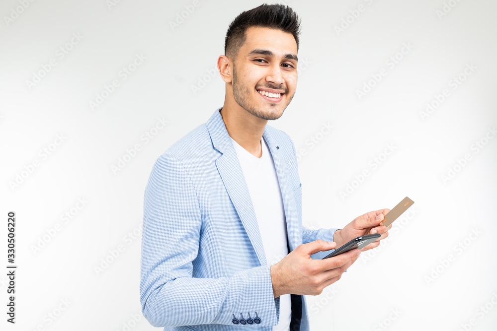 a man enters data with a credit card into a mobile phone to make a purchase via the Internet on a white background a man enters data with a credit card into a mobile phone to make a purchase via the Internet on a white background