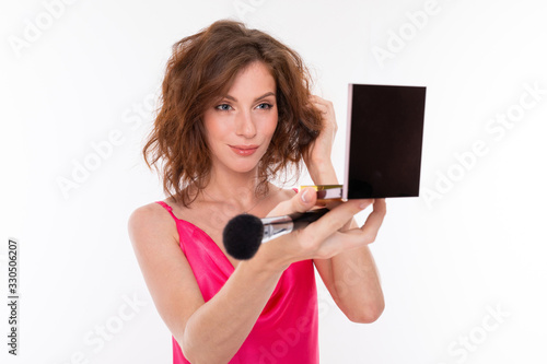 A young caucasian woman do makeup isolated on white background