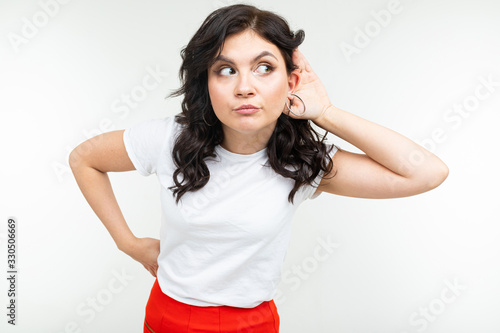 brunette girl in a white t-shirt eavesdrops on a conversation on a white background