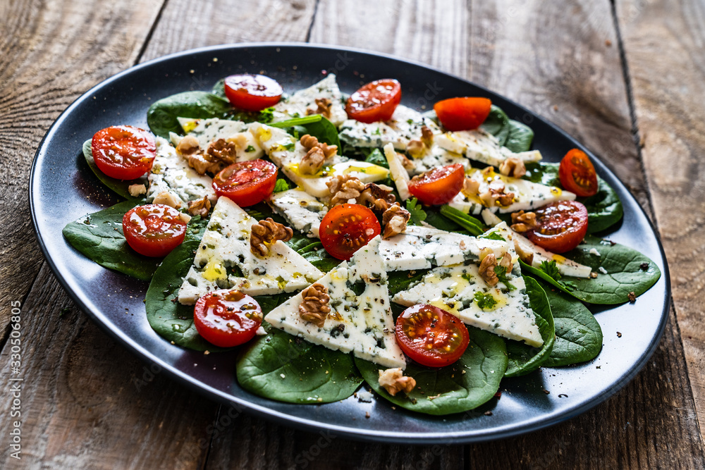 Fresh salad - blue cheese, cherry tomatoes, spinach, walnuts on wooden background Fresh salad - blue cheese, cherry tomatoes, spinach, walnuts on wooden background