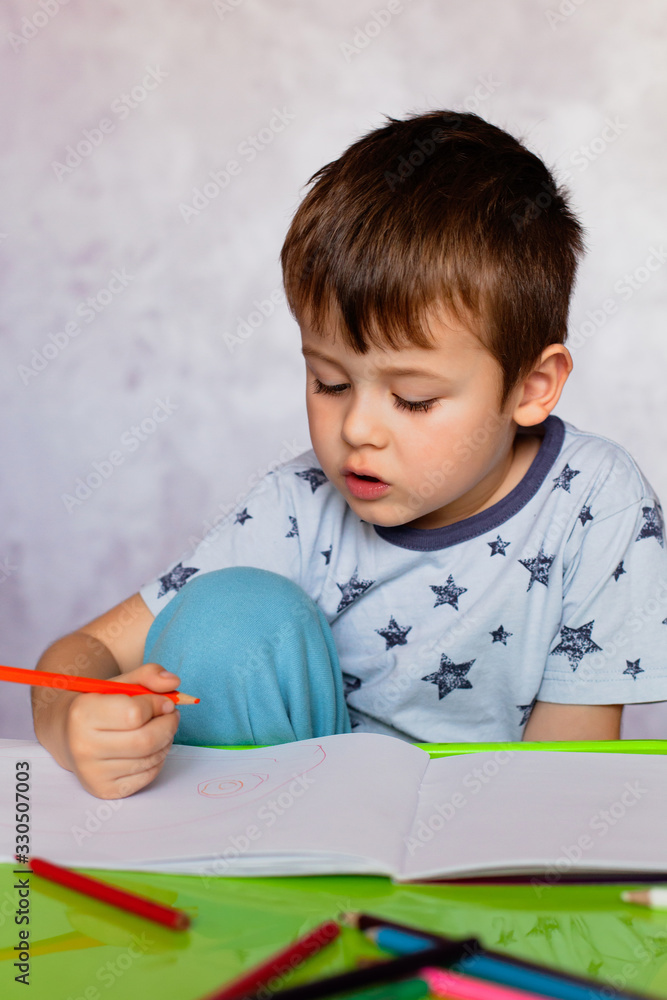 Little boy drawing with color pencils. Boy, drawing a picture for fathers day. Small boy draws at the table. Little boy drawing with color pencils. Boy, drawing a picture for fathers day. Small boy draws at the table.