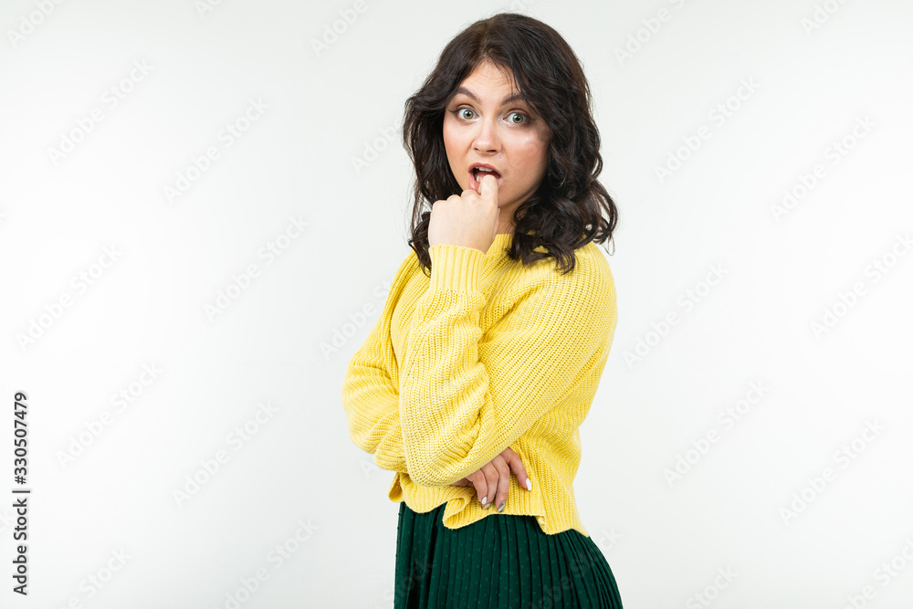 pensive brunette young woman in a yellow sweater and green skirt on a white background with copy space pensive brunette young woman in a yellow sweater and green skirt on a white background with copy space