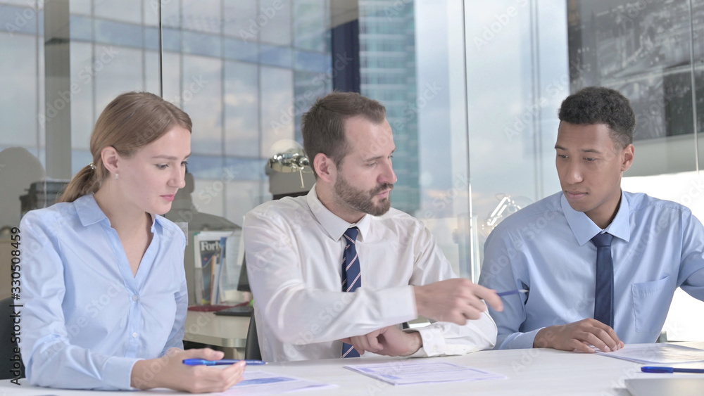 The Businessman Explaining on Documents to his Assistants in Office The Businessman Explaining on Documents to his Assistants in Office